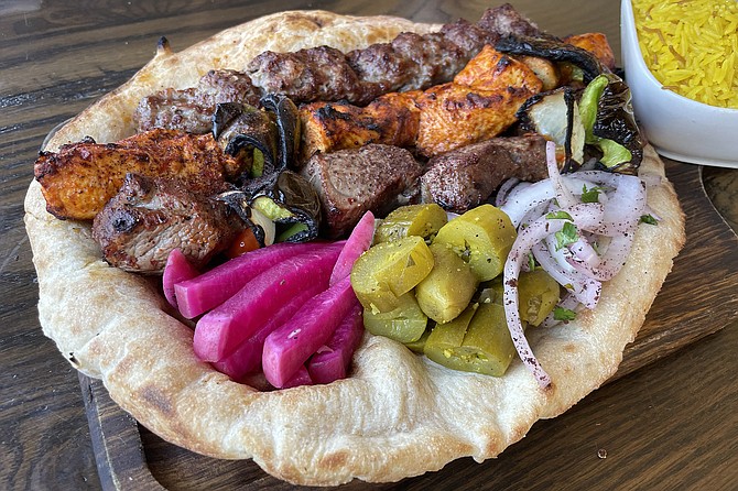 The mixed grill platter, served with pickled vegetables atop fresh tanour flatbread