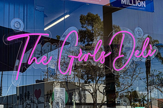 Pink neon signs light the way to The Girls Deli.