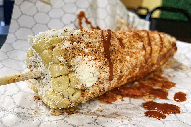 Elote, a.k.a. corn on the cob, slathered with mayo, cotija cheese, tajin, lime, and hot sauce