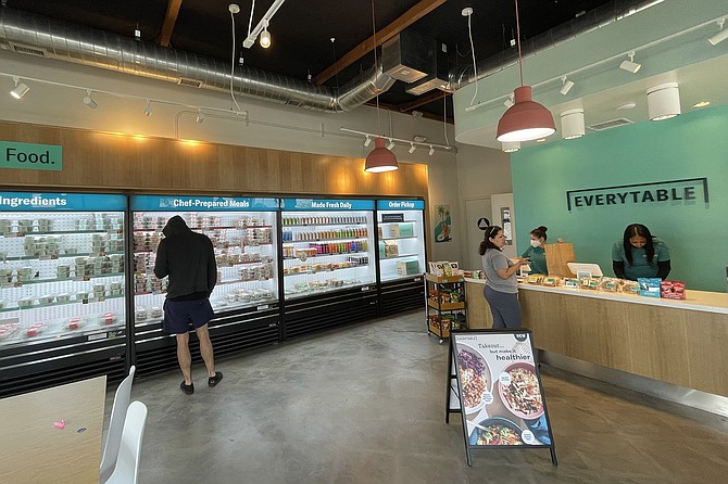 A small shop with coolers offering affordable, preprepared meals