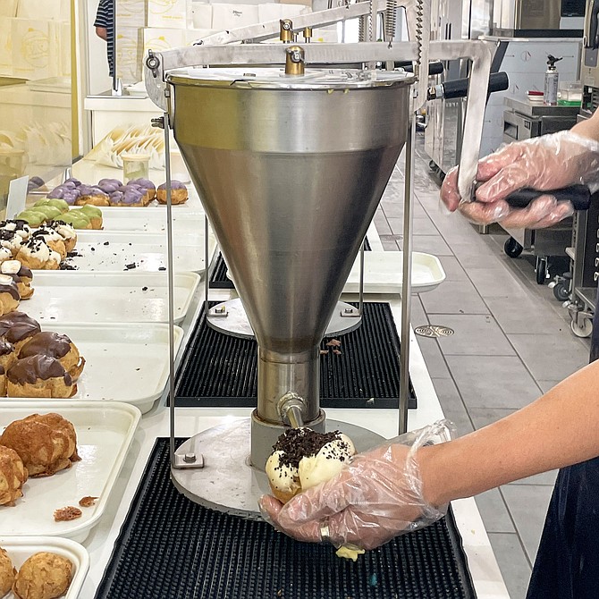 Behind the counter, a pump fills pastry shells with custard, to order.