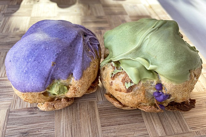 An ube cream puff filled with green tea custard and a green tea cream puff filled with ube custard