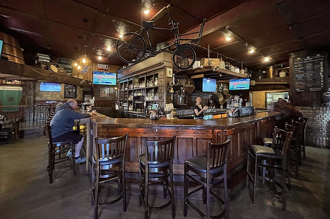 Friendly bartenders work behind the polished wood of an Irish pub.