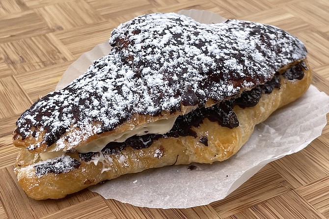 A decadent chocolate croissant, with confectioner's sugar and cream