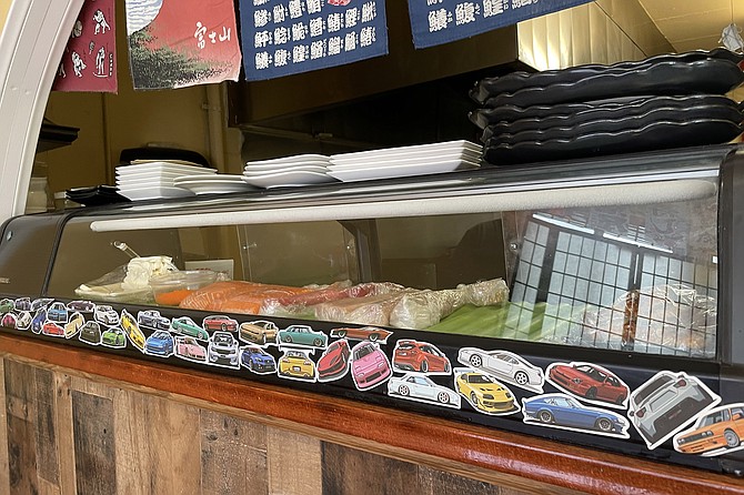 Car stickers cover the sushi cooler, prompting memories of Japanese street racing culture