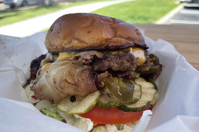 A single onion burger, with everything on it, including house-made pickles and pickled jalapeños