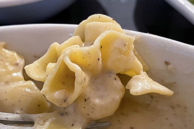 Stuffed pasta in the shape of candy in a single-twist wrapper, filled with truffle and ricotta cheese, n a creamy mushroom sauce