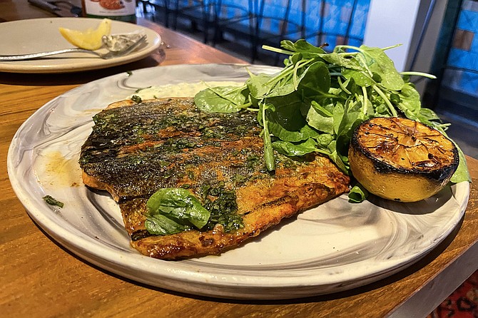 Wood grilled trout, served with watercress and blistered shishito peppers.