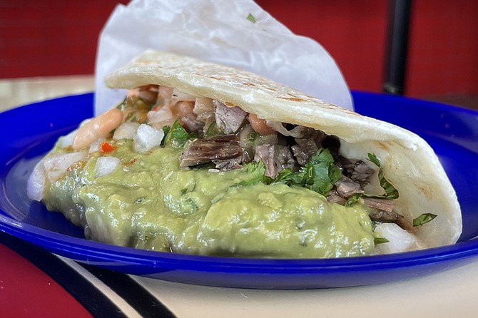 The signature machin, taco: carne asada, cheese, guacamole, and beans on a flour tortilla