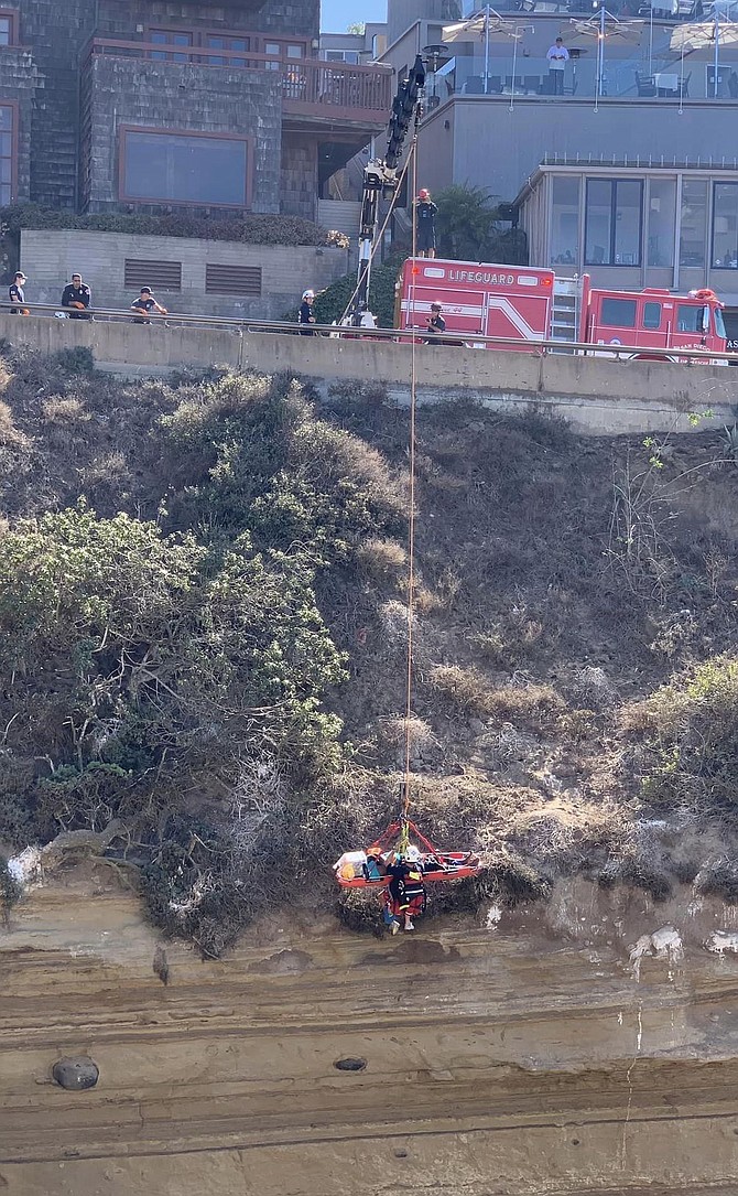 A fire truck crane extended over La Jolla Cove across the street.