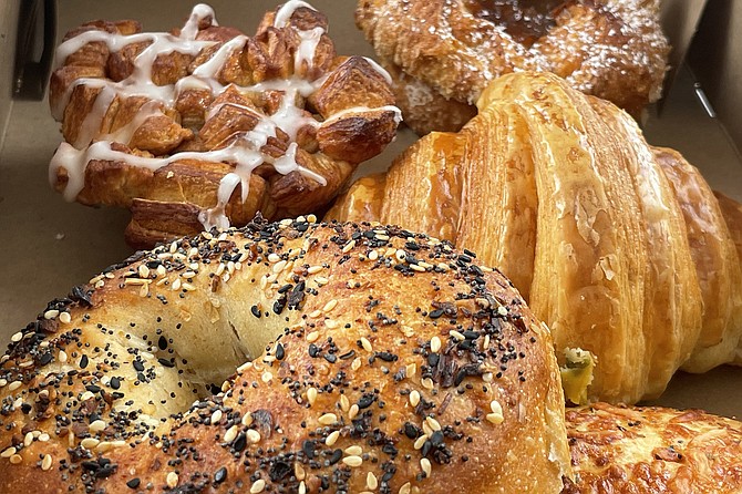 A variety of baked goods, including (front to back) bagel, croissant, monkey bread, and kouign amman.
