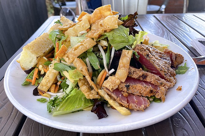 Spicy Asian salad with cajun seared ahi, romaine, mesclun, carrots, mandarin oranges, green onions, spicy roasted almonds, bean sprouts, crispy wonton strips, cilantro, and miso ginger sesame dressing