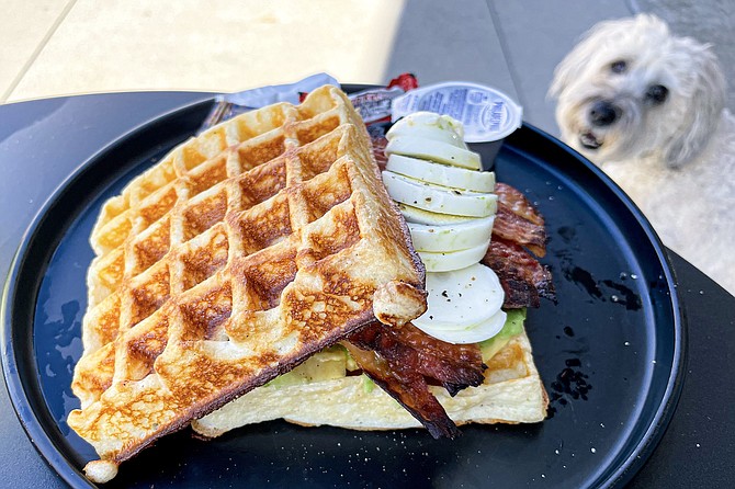 A waffle sandwich, with turkey, bacon, avocado, and hard-boiled egg — plus cream cheese, ketchup, and hot sauce packets on the side