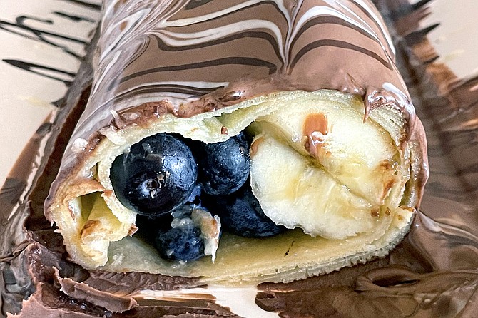 A crepe filled with blueberries and banana slices, then coated in three kinds of Belgian chocolate.