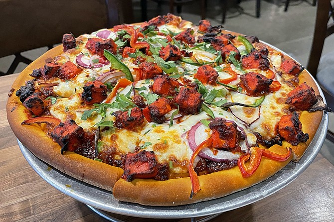 An Indian pizza, featuring paneer, curry leaf, onions, bell peppers, cumin, and szechwan peppers