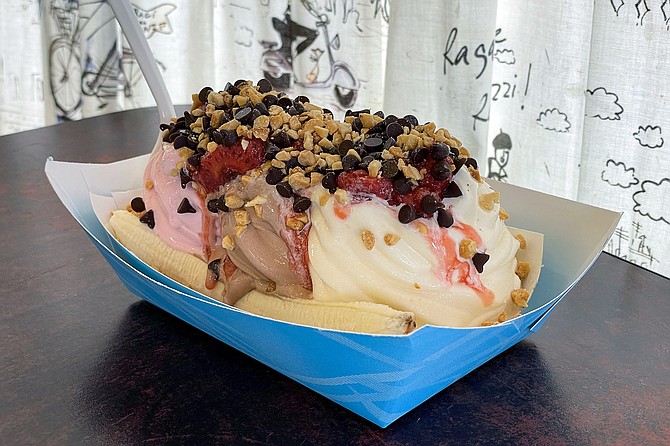 A frozen yogurt banana split, made with low-fat chocolate, nonfat vanilla, nonfat sugar-free raspberry yogurts, and topped with strawberries, chocolate chips, and crushed peanuts,