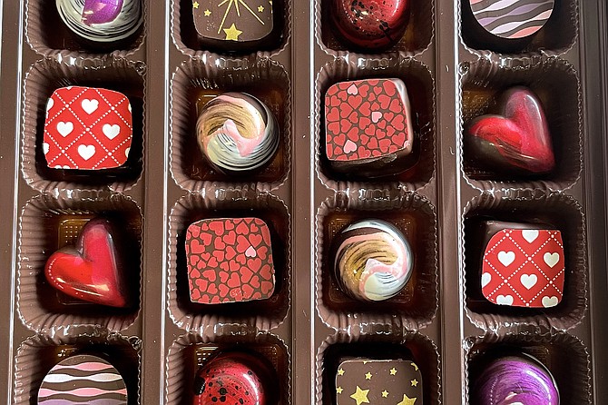 A box of chocolates, including several heart-shapes and colorful cocoa butter applications