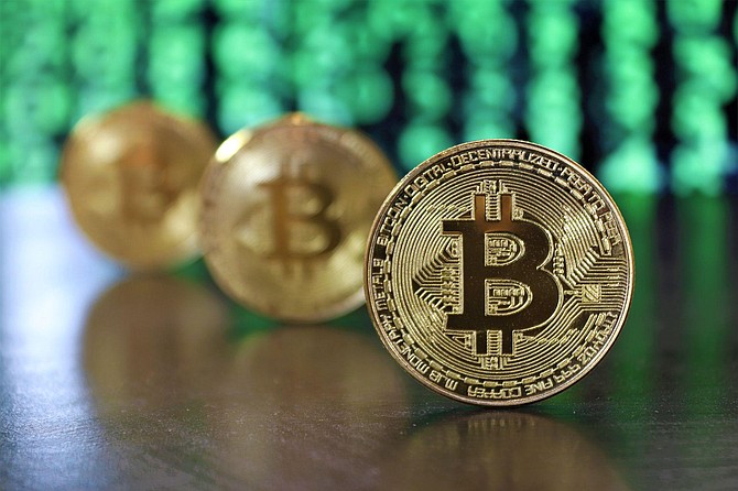 SPONSORED CONTENT Golden Bitcoin coins on a wooden table.