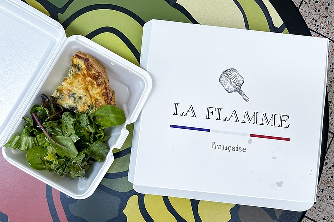 A broccoli and emmental cheese quiche, and salad, next to a pizza box filled with a "tarte flambée", and salad