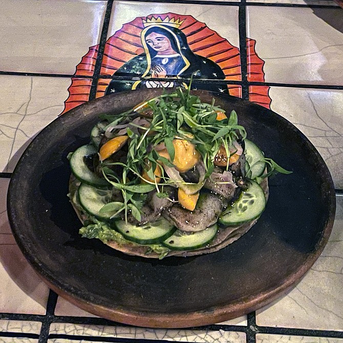 Scallop and uni aguachile, on a table tiled with religious iconography
