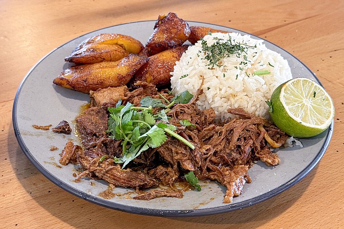 A Cuban-style mojo shredded pork served with rice and grilled plantains at Flama Llama