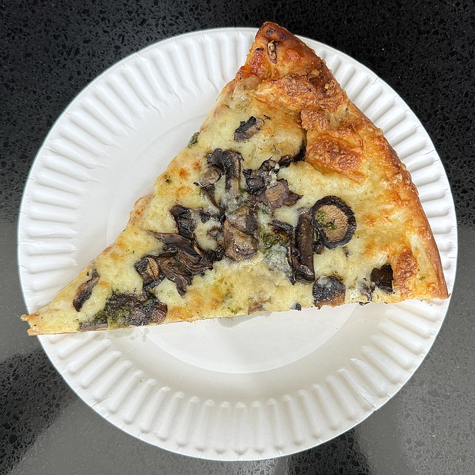 A slice of "Mushroom Medley" pizza, with a wine, butter, garlic, and shallot sauce.