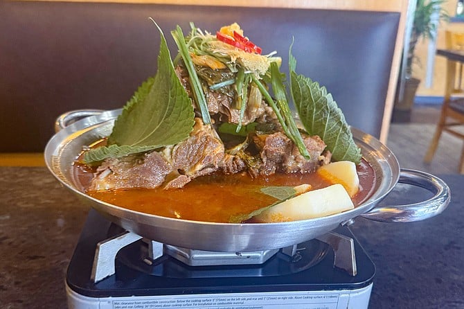 A pot of gam-ja-tang — a Korean pork neck stew — finished on a tabletop stove