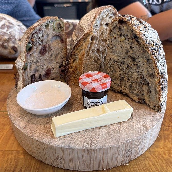Izola Bakerys counter display showing off the "sourdough flight," featuring three half-loaves with salt, jam, and butter