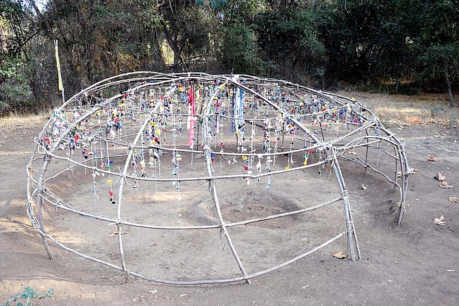 Hundreds of strings of prayer ties — relics of previous ceremonies — hang from the latticework of the sweat lodge frame, gently swaying in the wind.