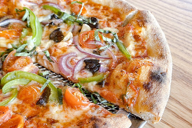 "The Veg," a vegetarian pizza (vegan optional) featuring cherry tomatoes, garlic confit, red onions, green bell peppers, sautéed mushrooms, and basil.