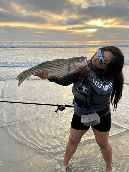 Lia ‘Yeezy’ Lao with her rare 26-inch striped bass caught from a San Diego beach