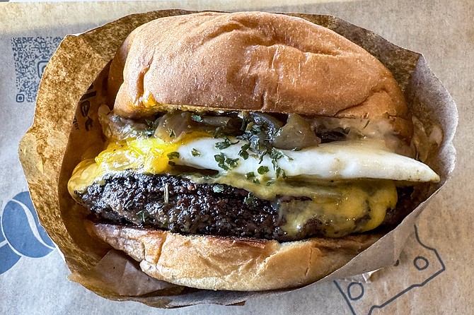 A cheeseburger topped with caramelized onions and over medium egg