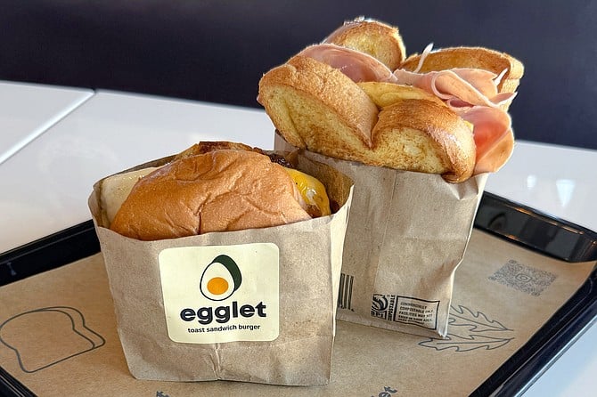 Egglets sandwiches are served upright, including a fried egg cheeseburger (left) and ham and cheese street toast (right)