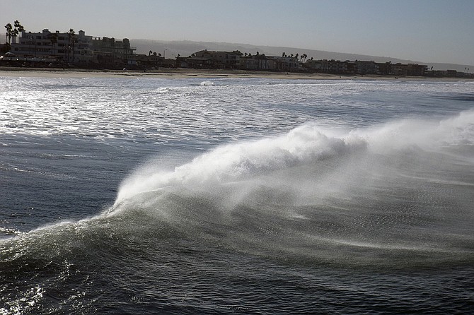 A hot morning in Imperial Beach and the Santa Ana winds are blowing offshore, producing a blast of sea spray as water and wind collide.