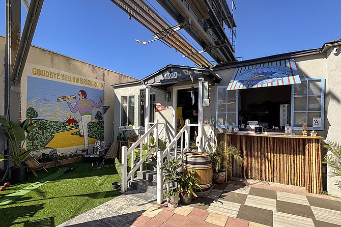 A sandwich shop in a house near the beach, with a billboard overhead