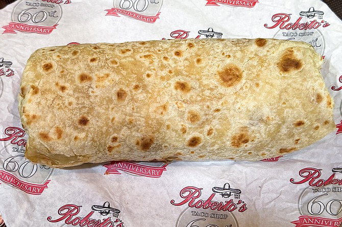 A California burrito, roughly the size of a man's forearm