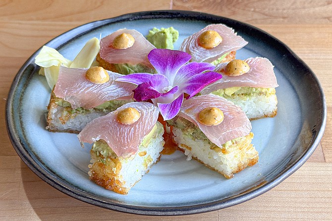 Sushi toast: crispy pats of rice topped with smashed avocado, sashimi, spicy garlic mayo, and ponzu, served in a pool of Peruvian Leche de Tigre.