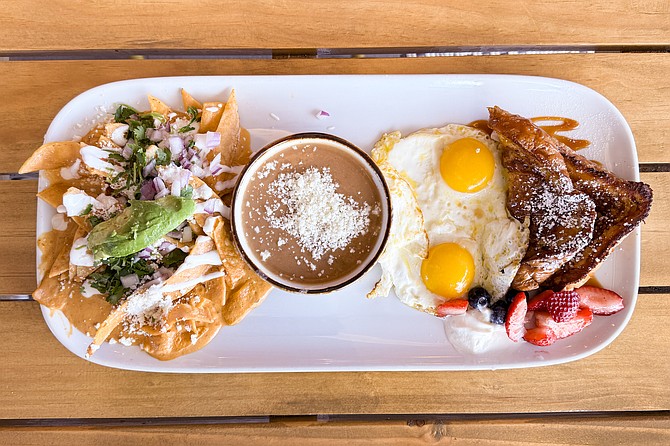 A sampler platter with chilaquiles, frijoles, sunny side up eggs, and Cajeta French toast