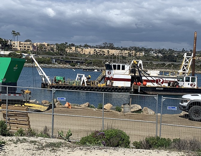 A dredger is positioned in the Agua Hedionda lagoon and sucks up the sand.
