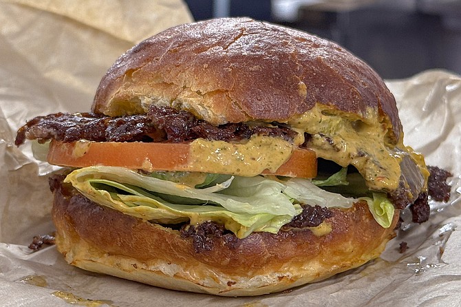 A smash burger with lettuce, tomato, and house-made chipotle spread