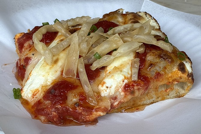 A deep dish pizza topped by cream cheese and wonton strips