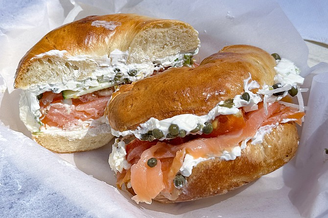 A lox sandwich with scallion cream cheese and capers, on plain bagel