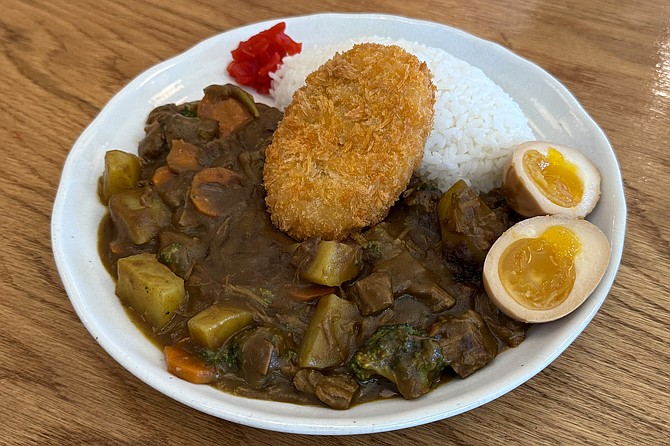 A Japanese curry beef stew with steamed vegetables and a potato croquette