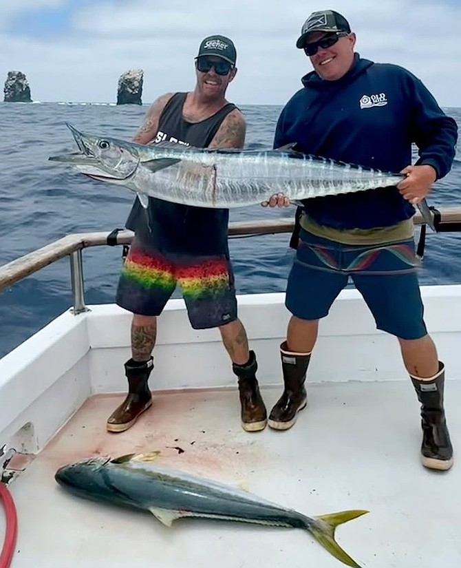 A solid wahoo in hand and a chunky yellowtail on the deck of the Searcher with Alijos Rocks in the background.