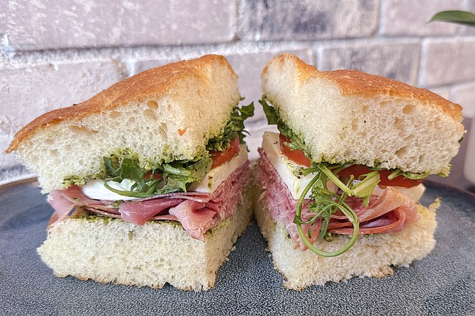 Prosciutto, salami, mozzarella, tomato, pesto, and arugula on fluffy foccacia bread