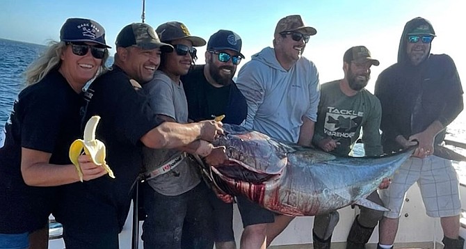 Tracy Hartman, posing with anglers and a hefty bluefin tuna on the Constitution in an effort to show that bananas on the boat are not "bad luck" after all.