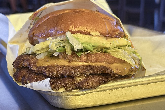 A double patty smashburger topped by lettuce, pickles, avocados, and a hash brown